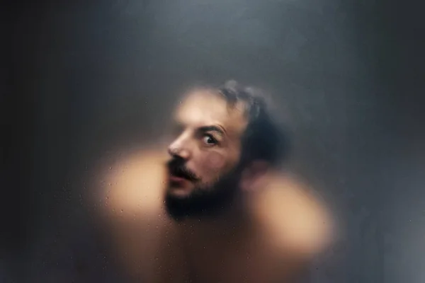 Creepy looking man with one eye behind a frosted glass. — Stock Photo, Image