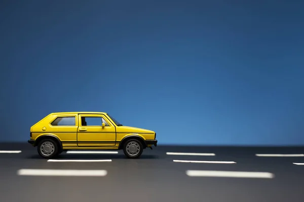 Yellow toy car with two doors on a blue background. — Stock Photo, Image