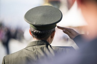 Resmi üniformalı komutan arka görüşten selamlar.