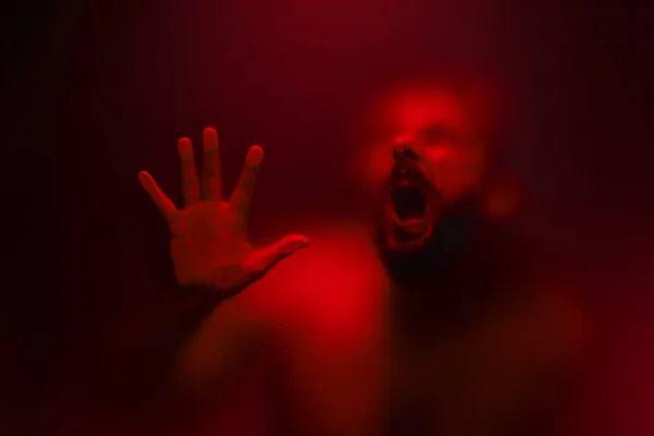 Creepy looking man is screaming behind a frosted glass. — Stock Photo, Image