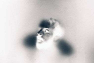 Buzlu cam arkasında bir gözü ile ürpertici görünümlü adam.