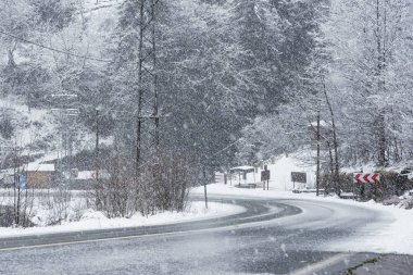 Kışın karlı yol manzarası, karlı ağaçlar, kayalar ve asfalt 