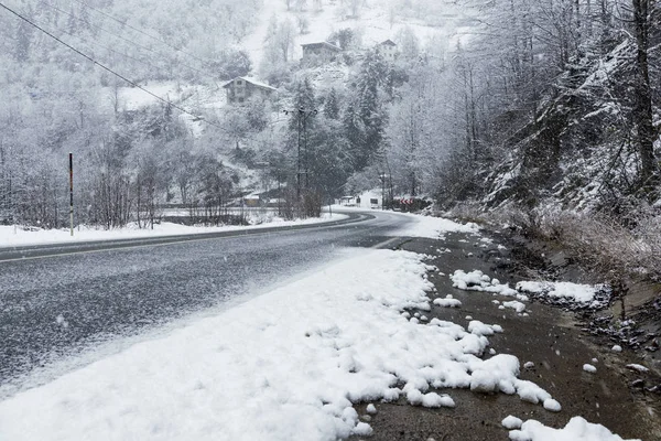 Снежная сцена на дороге зимой, со снежными деревьями, скалами и асфальтом — стоковое фото