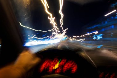 Uzun pozlama ve sallantılı bir araba ve sürücünün gözleri gece yolda hız yapıyor..