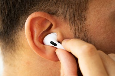 Beyaz renkli Apple Airpod 'ları bir erkeğin kulağına yakın plan çek.