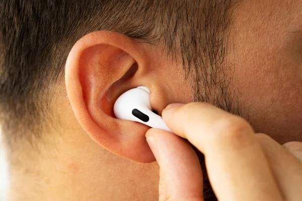 Beyaz renkli Apple Airpod 'ları bir erkeğin kulağına yakın plan çek.