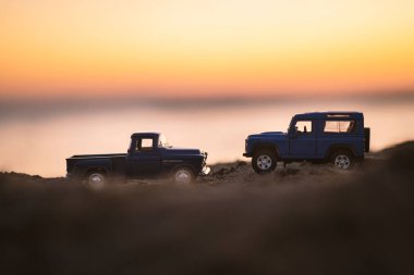 İzmir, Türkiye - 22 Ağustos 2020: Bir Chevrolet 3100 kamyonet ve bir mavi renkli arazi aracı kum üzerinde ve gün batımında yakın çekim.