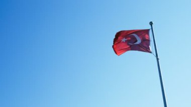 Bayrak direğinde Türk Bayrağı ve mavi gökyüzü arka planında.