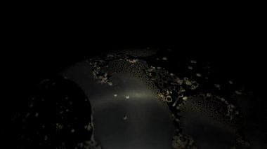 Soyut altın renkli şekiller bir baloncuğun yüzeyinde ve siyah bir arkaplanda filme alınır.