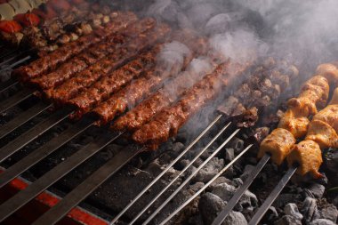  Soğan, domates, tavuk, şiş kebap ve et şiş şiş şiş ızgaranın üstünde ızgara yaparken dumanlı tatlar ve canlı renklerle fotoğraf çekmek.