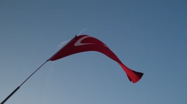 İzmir 'in kurtuluş yıldönümünde gökyüzüne doğru sallanan Türk bayrağını yakalayan yavaş çekim videosu, arka planda bir jet uçuşu gerçekleştiriyor.