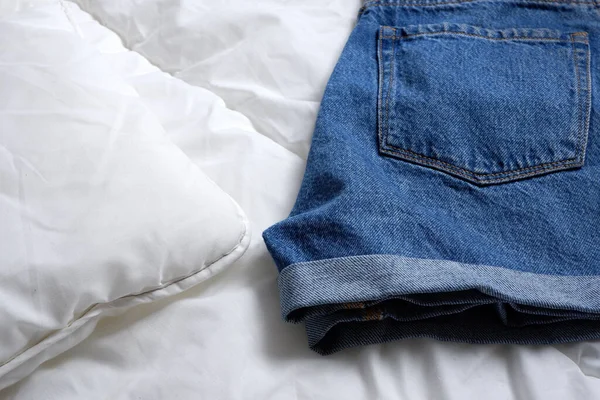 Denim shorts on a white blanket.  Background. Minimalism