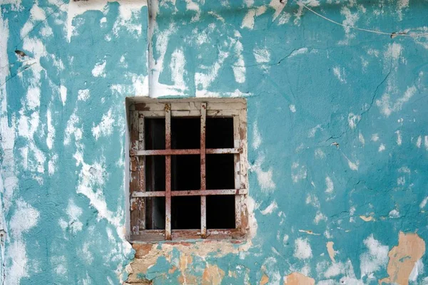 蓝色破墙上有一座废弃旧房子的金属百叶窗的旧窗户 — 图库照片