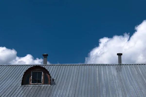 iron roof with attic window on blue sky background