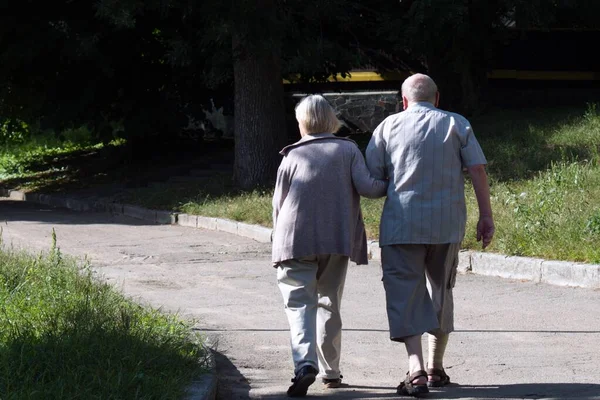 elderly man and woman walking down the path in park