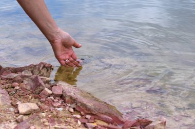 Bir orman gölünün berrak soğuk suyuna dokunan el.