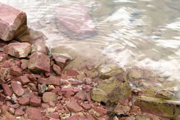 海岸の赤い石と砂森の湖の澄んだ水の中で — ストック写真