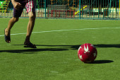 Teenager spielt mit Fußball auf der grünen Wiese