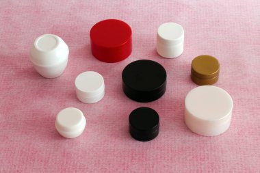 Beyaz pembe kumaş üzerine kozmetolojik ürünler paketlemek için küçük kavanozlar