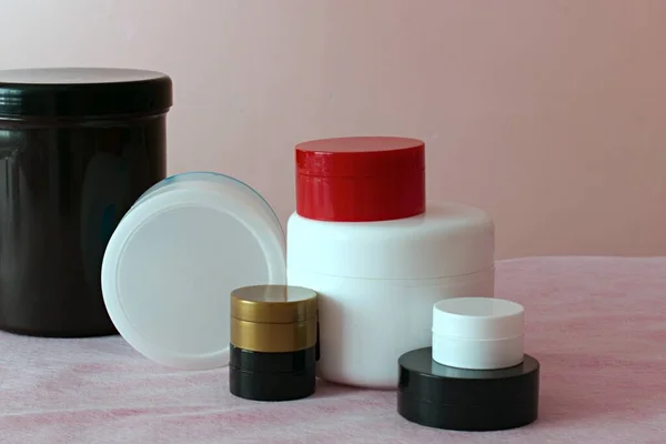 Plastik kavanozlar beyaz pembe bulanık arka planda kozmetolojik ürünler paketlemek için