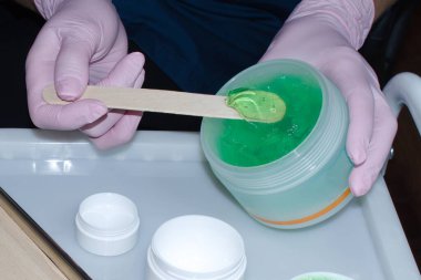 Eldivenli eller büyük bir konteynırdan küçük bir konteynıra kozmetik jel koydu.