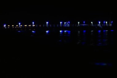 Denizdeki bulanık yansıması ile marinanın çok renkli lambalarının gece aydınlatması