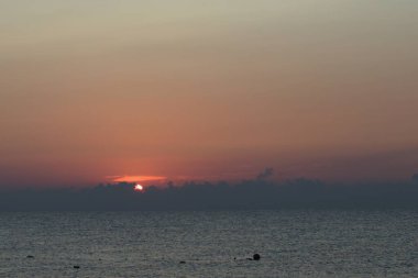 Sabah şafağı. Bulanık ufukta yükselen kırmızı güneş ve gri bulutlar.