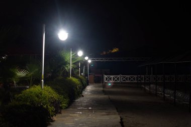 Lambaların parlak ışığı gece sahil boyunca sokağı aydınlatıyor.