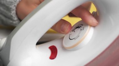 Kadın eli, demir güç düğmesini maksimuma çıkarır. Çamaşır ütüleme konsepti