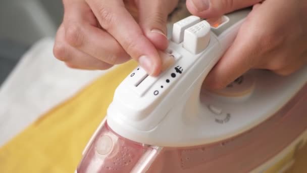 Female hand switches steam mode on iron and presses button. Girl ironing linen concept — Stock Video