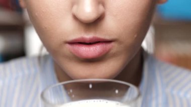 Kadın süt içiyor. Kadın eli ağzına cam dayayıp süt içer.