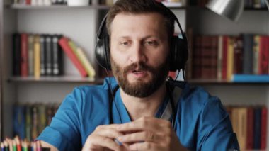 Doktor cerrah kamerayla konuşuyor. Çekici sakallı cerrah, kameraya bakarken bir şeyi detaylı bir şekilde açıklıyor.