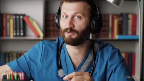 Doktor chirurg mluví s kamerou. Atraktivní vousatý chirurg drží v ruce falešné umělé srdce a něco říká, zatímco se dívá do kamery — Stock video