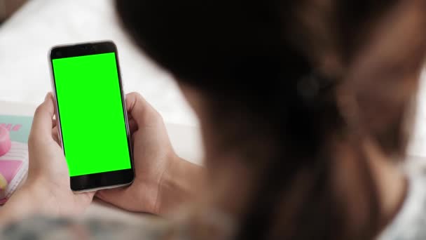 A mulher olha para a tela verde do telefone celular e fala sobre a conexão de vídeo online e às vezes acena aprovadamente ao interlocutor. Close-up — Vídeo de Stock