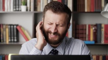 Kulak ağrısı. İş yerindeki üzgün adamın yakın çekimi, kulağına dokunur ve acı hisseder. FurUncle, kulak kiremitleri, egzama, kulak hastalığı, otitis medya konsepti