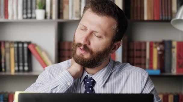 Dor no pescoço. Close-up do homem barbudo no local de trabalho, ele experimenta dor intensa no pescoço, toca seu pescoço com a mão e faz movimentos de cabeça constrangidos. Conceito de osteocondrose cervical — Vídeo de Stock