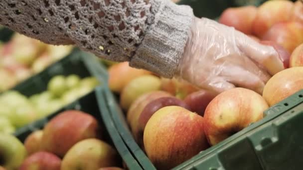 La mano femminile in guanto raccoglie mele di frutto in cesto in supermercato. Primo piano — Video Stock