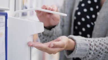 Kadın süpermarkette elini dezenfekte ediyor. Yakın plan.