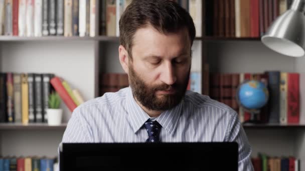 Han jobbar vid datorn. Fokuserat skägg manliga arbetare frilansare affärsman säljare på arbetsplatsen skriva på laptop tangentbord skriver in data och dricka kaffe eller te. Närbild — Stockvideo