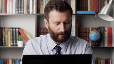 İş yerindeki huysuz adam dizüstü bilgisayarda yazı yazıyor ve homurdanıyor, küfrediyor. Müdür sendromu, tükenme, stres, iş sorunları, olumsuz tepkiler, hayal kırıklığına uğramış çalışan konsepti. Yakın plan.