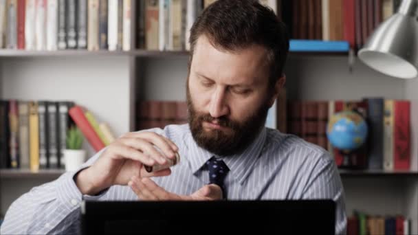 Prendre des pilules. L'homme au travail met la tablette dans sa bouche et la boit avec de l'eau, en tapant sur le clavier de l'ordinateur portable. Gros plan — Video