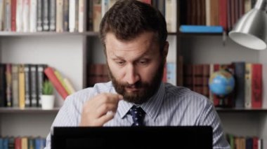Göz yorgunluğu, yönetici sendromu, yorgunluk, stres, aşırı çalışma, uyku bozukluğu konseptleri. İş yerindeki yorgun sakallı adam dizüstü bilgisayarda çalışıyor, kırılıyor ve gözlerine damlıyor. Yakın plan.