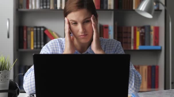 Baş ağrısı. Kadın iş yerinde bilgisayar başında çalışıyor, eller alnına ve geçici bölgesine dokunuyor, kafasında ağrı hissediyor. Yüksek tansiyon, yorgunluk, stres konsepti. Orta boy. — Stok video