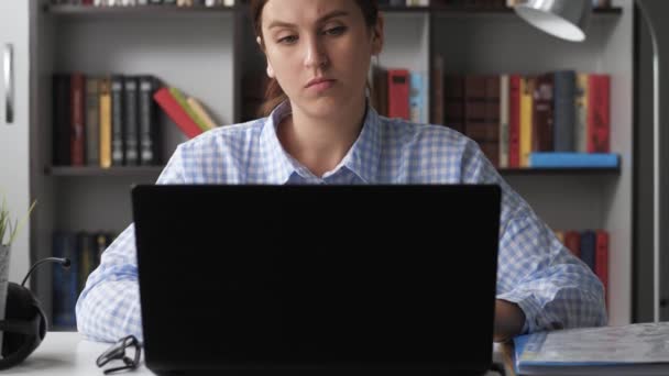 Pain in neck. Woman works at computer, she experiences pain in neck and touches her neck with her hands, turns her head in attempt to relieve pain. Osteochondrosis concept. Medium shot — Stock Video