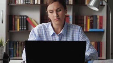 Bilek ağrısı. Kadın bilgisayar başında çalışıyor, bileğinde ağrı hissediyor ve üzgün, diğer eliyle ağrıyan koluna dokunuyor. Orta boy.