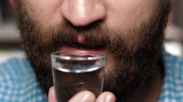 De man met de baard drinkt wodka. man hand brengt stapel naar zijn mond en drinkt wodka — Stockvideo