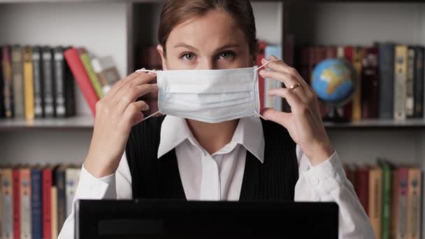 Koncepcja pandemii coronavirus covid-19. Pozytywnie atrakcyjna kobieta zakładająca maskę chirurgiczną na twarz i patrząca w kamerę. Zbliżenie — Wideo stockowe