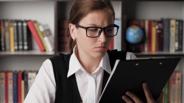 Εστιασμένη γυναίκα με γυαλιά διαβάζει προσεκτικά τα έγγραφα, γυρίζει σελίδα. Κοντινό πλάνο — Αρχείο Βίντεο