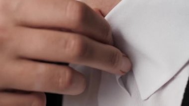 Gömleğinin düğmelerini açan kadın, ısı konsepti. Kadın eli, beyaz gömleğin üst iki düğmesini çözer. Yakın plan.