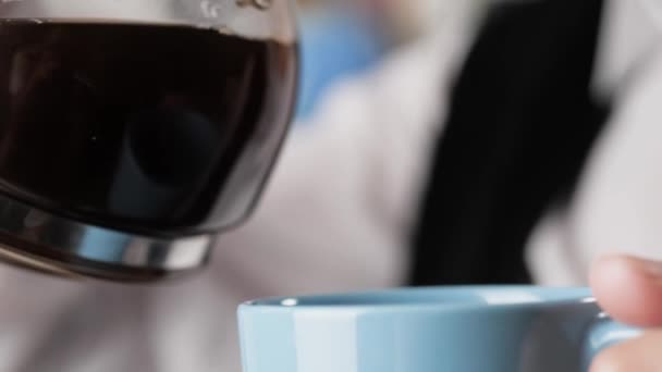 La mujer vierte café. Vista de cerca de la mano femenina vierte café de la cafetera en taza azul — Vídeos de Stock
